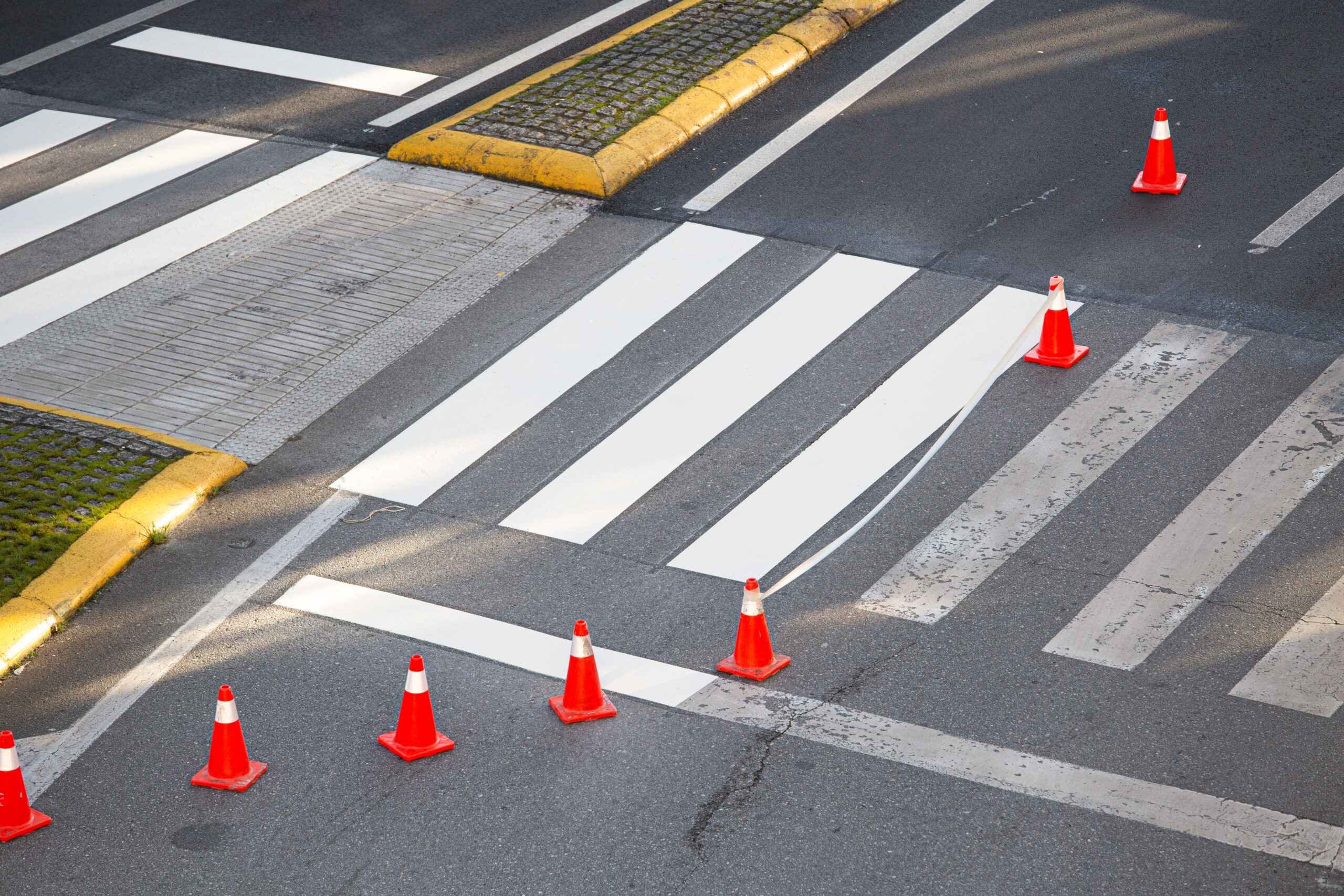 Zebra crossing in the process of being painted with masking tape and traffic cones on a city road. No people